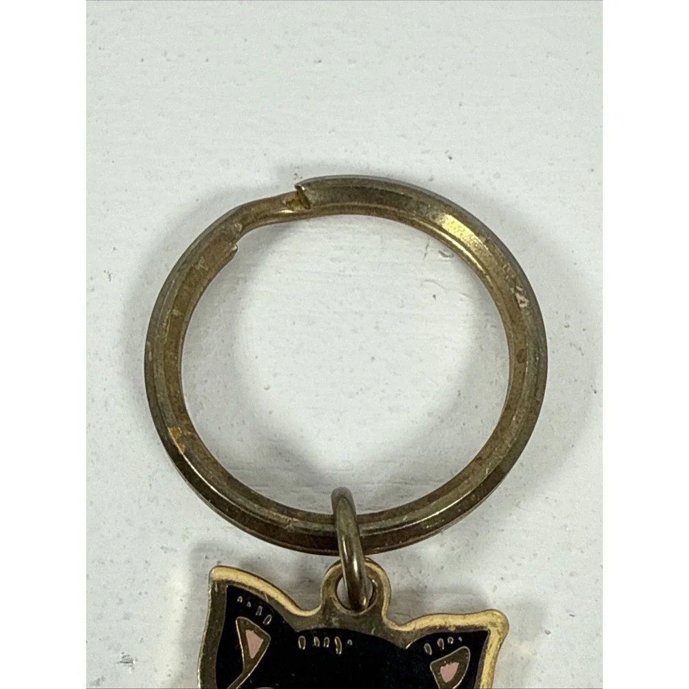 Black cat enamel keychain with gold-toned metal accents and a red bow